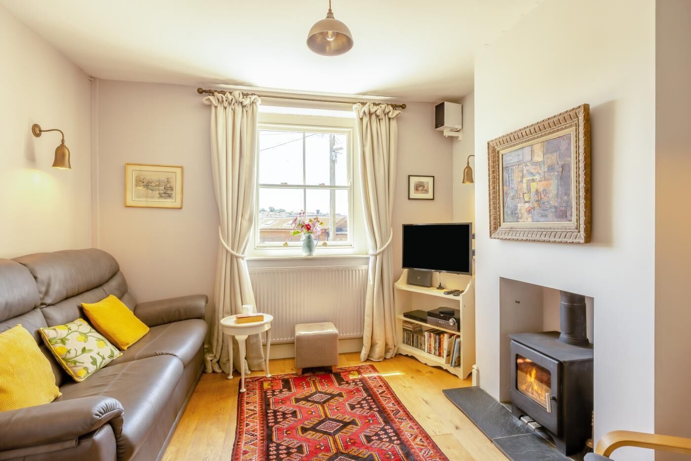 A living room with a sofa, a fireplace, a television, and a bookshelf.