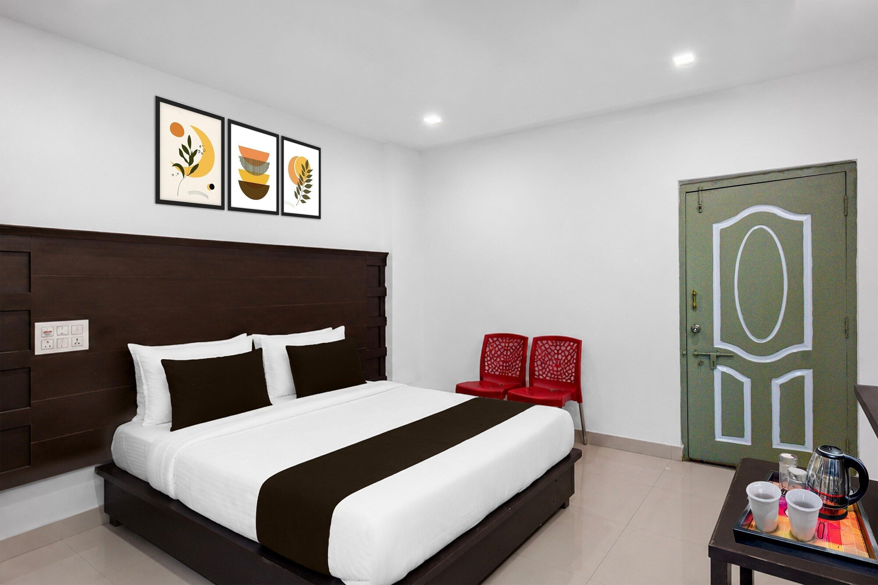 Una camera d'albergo con un letto, un tavolino con un bollitore, tazze e un vassoio, e una porta verde con un motivo geometrico bianco.
