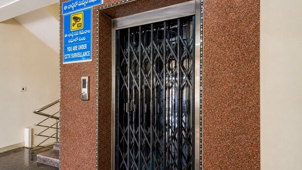 Um portão de segurança com aviso de vigilância por circuito fechado, um portão de metal e uma escadaria.