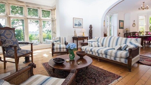 A spacious living room with a large window, a sofa set, and a dining area. - 4 Bed in Wareham (oc-dc182) (West Lulworth)