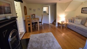 Una sala de estar acogedora con chimenea, un comedor con muebles de madera, un sofá y una mesita de noche con lámpara.