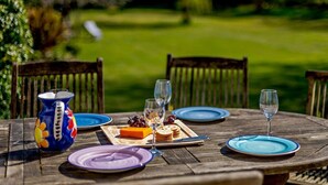 A wooden table set outdoors with plates, glasses, a vase, and food items. - 4 Bed in Wareham (oc-dc204) (West Holme)