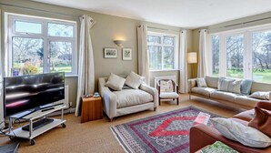 A living room with a TV, sofas, a rug, and large windows. - 4 Bed in Wareham (oc-dc204) (West Holme)