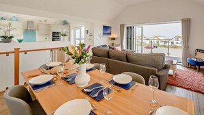 Una sala de estar moderna con comedor, cocina y vistas al exterior.