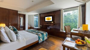 Quarto de hotel com uma cama grande, uma escrivaninha com cadeira, televisão e vista para o exterior.