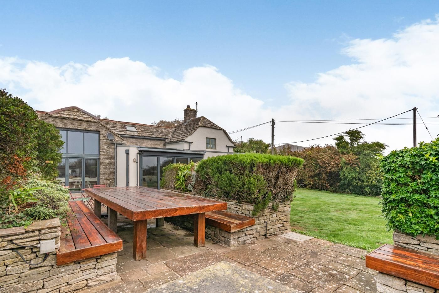 A house with a stone exterior, a wooden deck, and a well-maintained lawn.