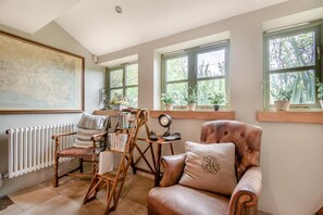 A room with a large map on the wall, a radiator, a leather armchair, a wooden chair, and a small table with books and a mirror. - 5 Bed in Swanage (oc-dc201) (Worth Matravers)