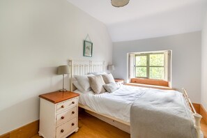 Ein Schlafzimmer mit einem Bett, Nachttischen, einem Fenster und einem Bild an der Wand.