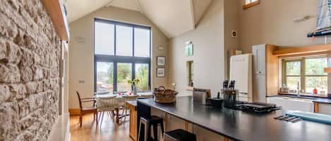 Una cocina con un amplio ventanal, suelo de madera y pared de piedra.