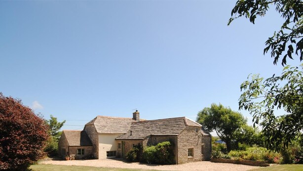A stone house with a sloped roof, a front lawn, and surrounding vegetation. - 5 Bed in Swanage (oc-dc201) (Worth Matravers)