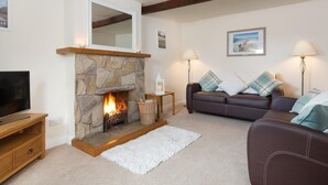 Ein Wohnzimmer mit Kamin aus Stein, einem Fernseher, einer Couch und einer Lampe.