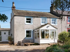 Ein zweistöckiges Haus mit weißer Fassade, einer Veranda und einem Wintergarten.