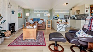 Una sala de estar acogedora con chimenea, un sofá, una mesa de centro y un comedor con una cocina al fondo.