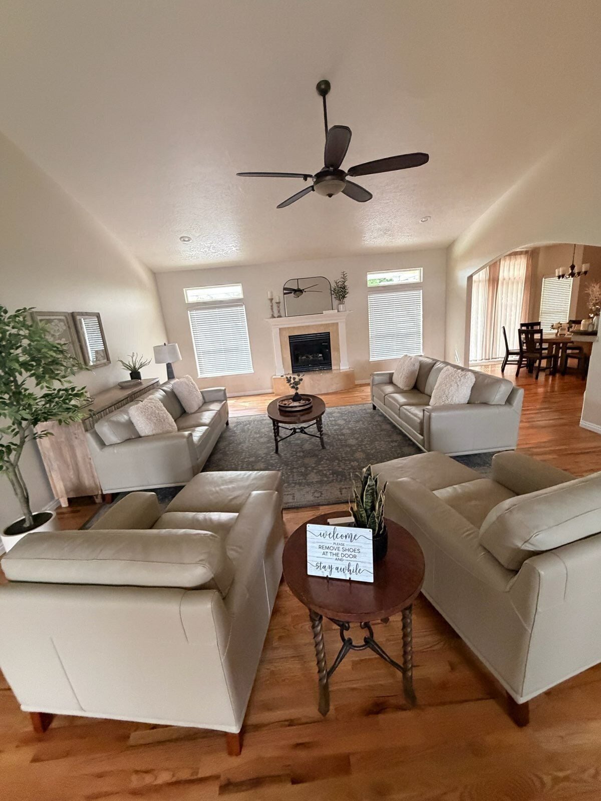 A spacious living room with a fireplace, two sofas, a coffee table, and a ceiling fan.