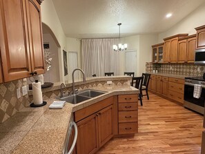 Eine Küche mit Granit Arbeitsplatten, Holzschränken, einer Edelstahlspüle und einem eingebauten Backofen.