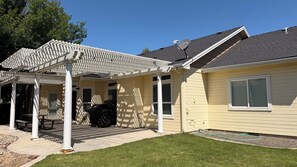 A house with a covered patio, a lawn, and a satellite dish.