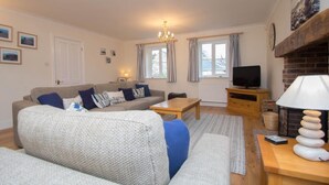 Ein gemütliches Wohnzimmer mit einer Couch, einem Fernseher, einem Kamin und einer Deckenleuchte.