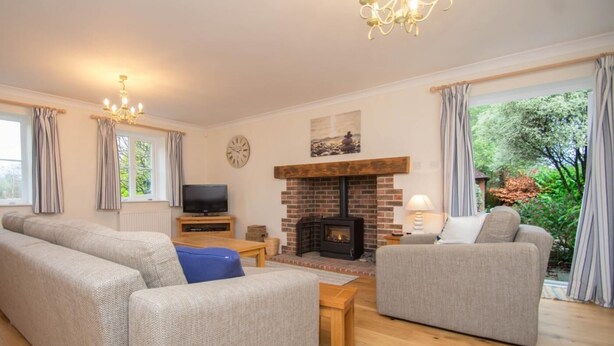 Ein Wohnzimmer mit Kamin, Sofas, einem Fernseher und einer Wanduhr.