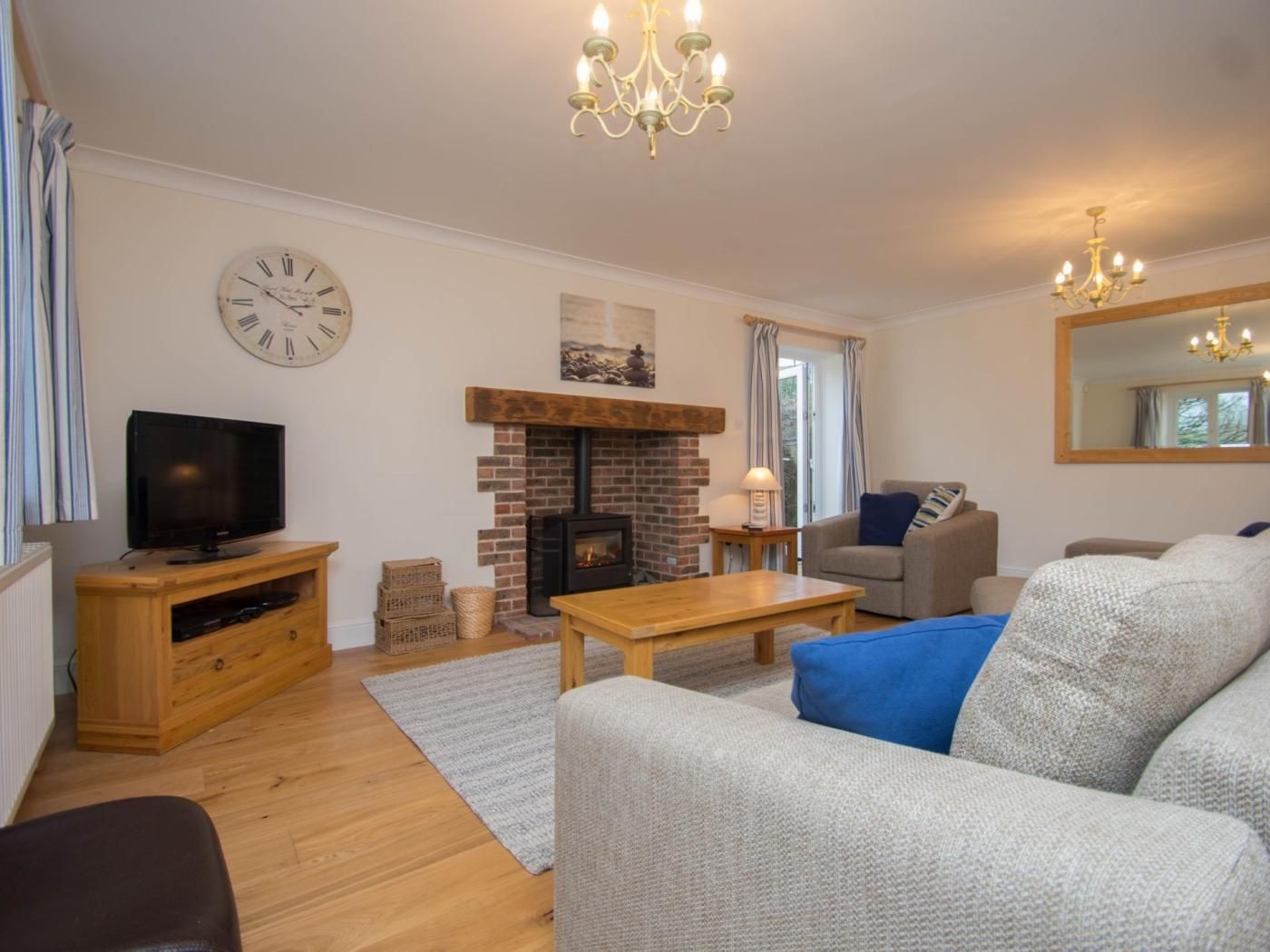 A living room with a television, fireplace, sofa, and a chandelier.