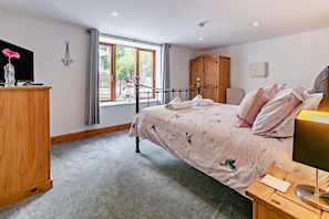 A bedroom with a bed, a wooden wardrobe, a desk with a lamp, and a window with curtains. - 6 Bed in Bideford (oc-75553) (Buckland Brewer)