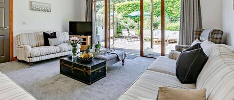 A living room with a sofa, a coffee table, a TV, and a sliding glass door leading to an outdoor area.