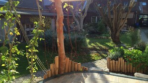 A garden with a wooden pergola, stone pathway, and various plants.