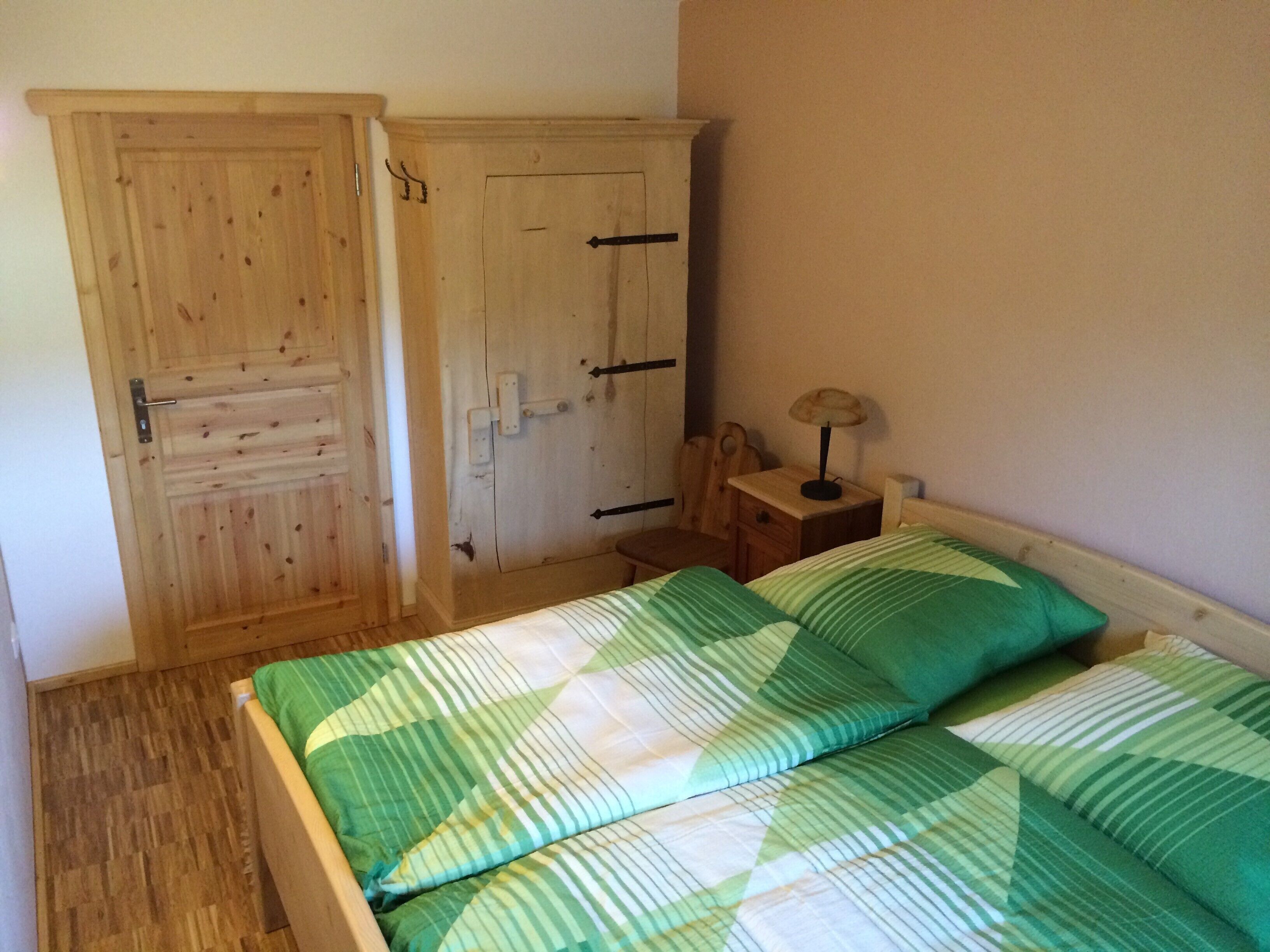 Une chambre à coucher avec une armoire en bois, une table de chevet avec une lampe et un lit avec une literie à rayures.