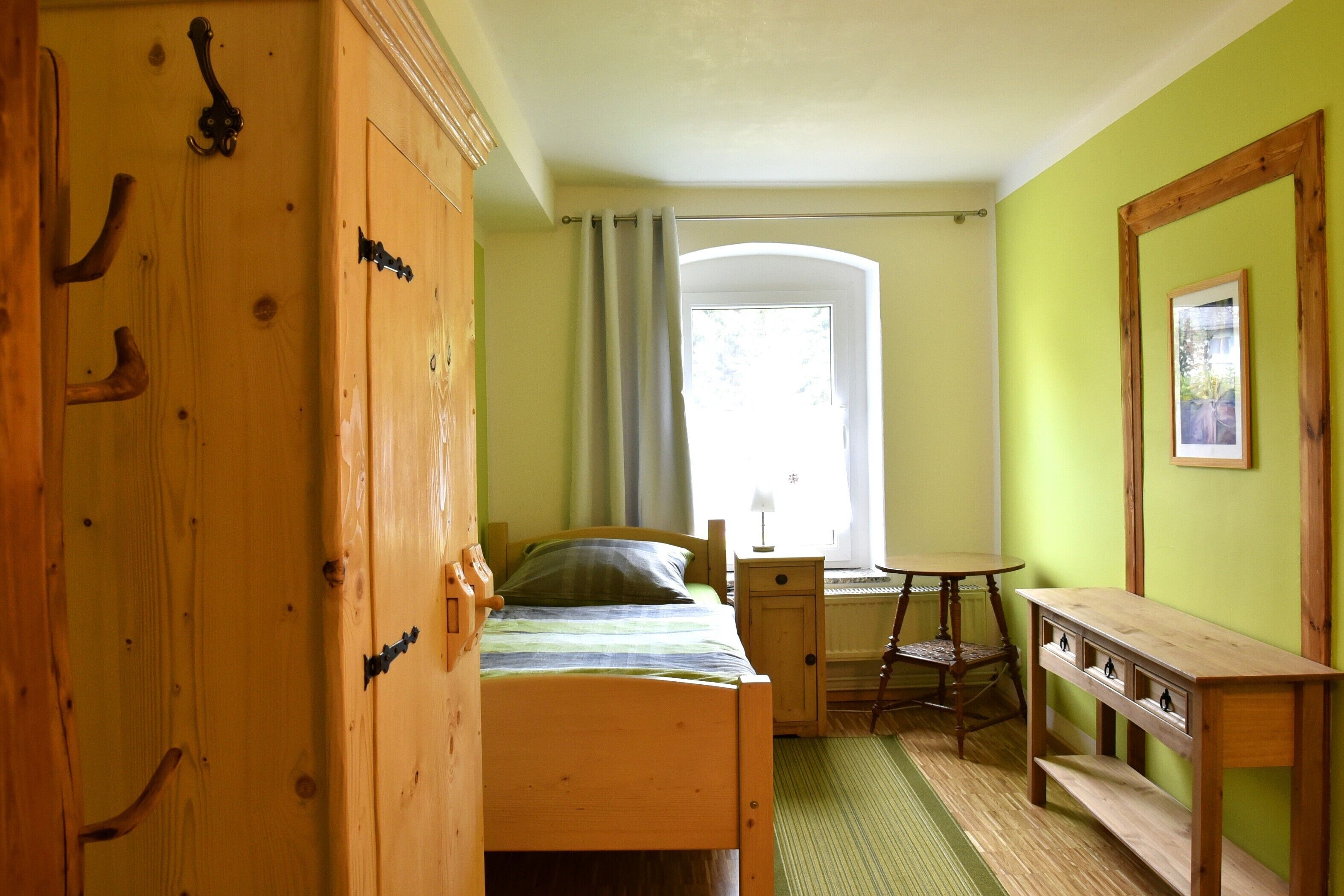 A room with a bed, a desk, a chair, and a small table.