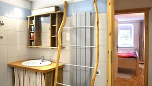 A bathroom with a wooden shelf, a sink, and a mirror.