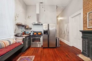 A compact kitchen with a stove, oven, and refrigerator, a small dining area with a table and chairs, and a cozy seating area with a sofa. - Relaxing Bohemian Villa w/ Heated Pool 5br 4ba (New Orleans)