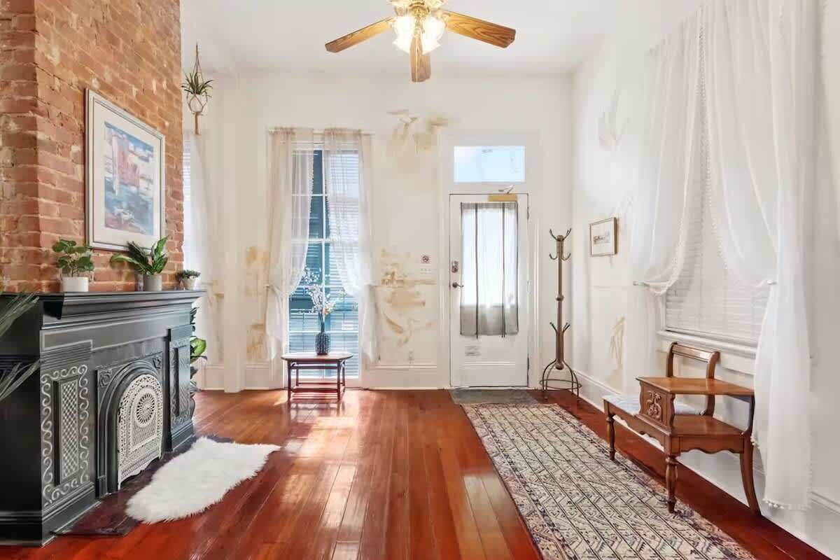 Ein Zimmer mit Holzdielenboden, Kamin, Deckenventilator und einer Tür mit Fenster.