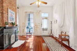 Une pièce dotée d’un plancher en bois franc, d’une cheminée, d’un ventilateur de plafond et d’une porte avec une fenêtre.