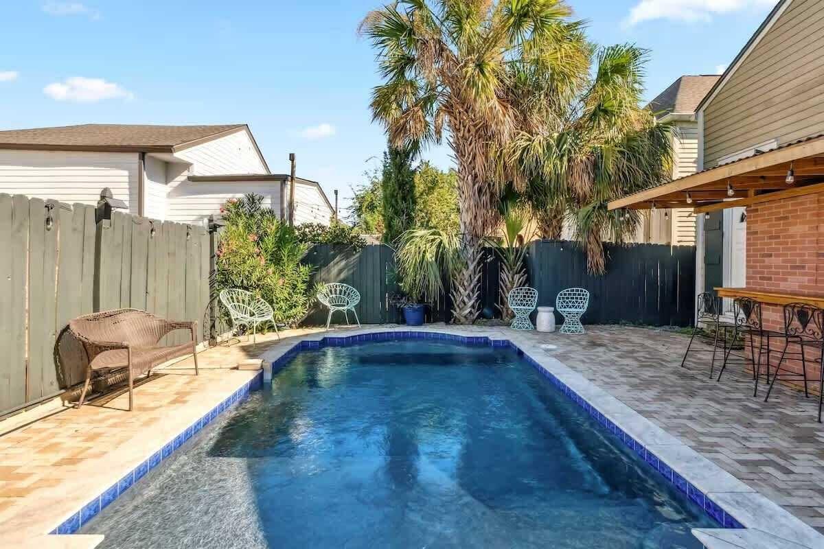Ein Garten mit Swimmingpool, Terrassenmöbeln und einem Holzzaun.