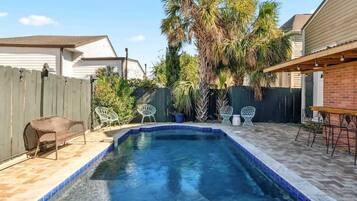 Ein Garten mit Swimmingpool, Terrassenmöbeln und einem Holzzaun.