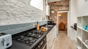 A narrow kitchen with a gas stove, a toaster, and a bread loaf on the counter. - 2 Bed in Brixham (oc-75550) (Brixham)