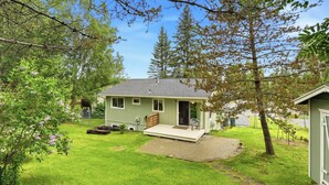 Ein kleines, eingeschossiges Haus mit Veranda, Garage und gepflegtem Rasen.