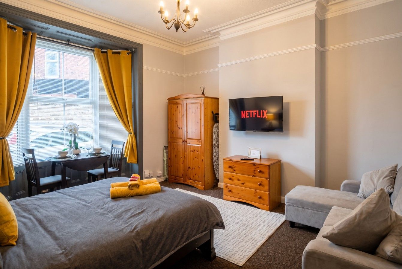 Studio room with bed, sofa, wardrobe and dining set in the bay window.