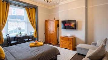 Studio room with bed, sofa, wardrobe and dining set in the bay window.