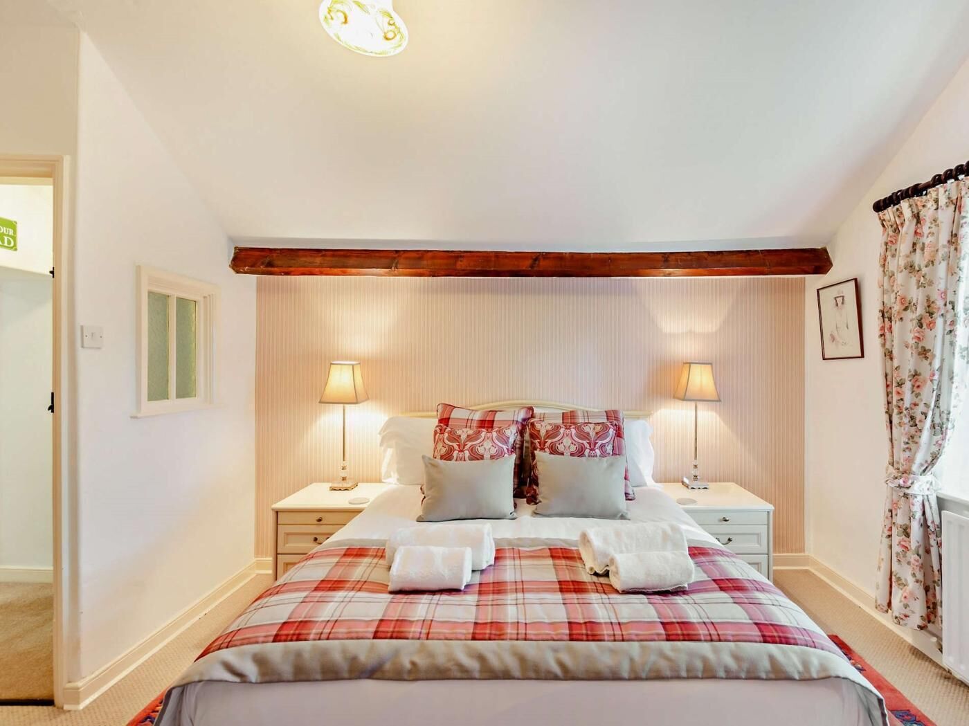 Una camera da letto con un letto, due comodini, una finestra con tende e una porta.