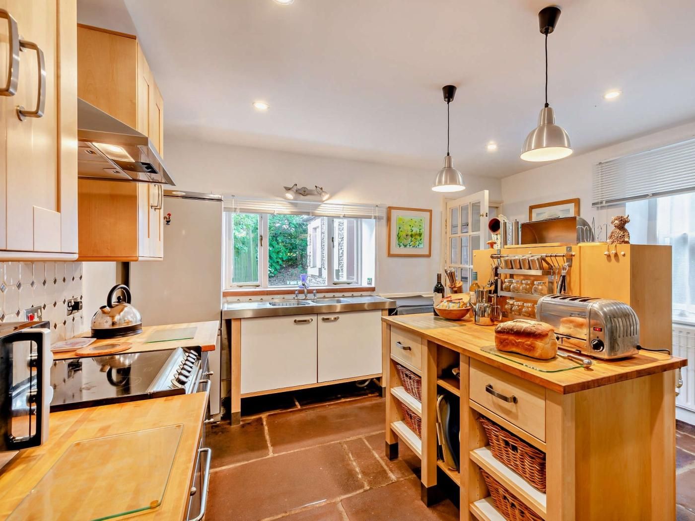 Une cuisine moderne avec des meubles en bois, un îlot central et une fenêtre qui laisse entrer la lumière naturelle.