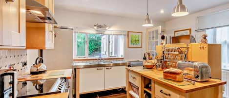 Une cuisine moderne avec des meubles en bois, un îlot central et une fenêtre qui laisse entrer la lumière naturelle.