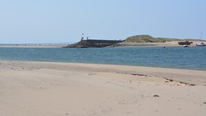 A beach with a rocky breakwater, calm water, and a distant shoreline. - 3 Bed in Dolgellau (oc-75737) (Dolgellau)