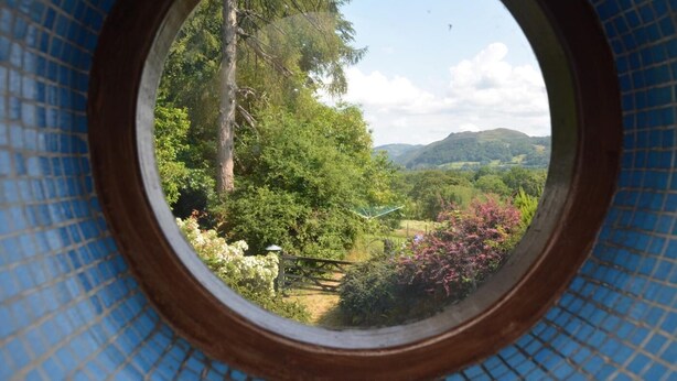 A circular window with a view of a lush landscape, including trees and hills. - 3 Bed in Dolgellau (oc-75737) (Dolgellau)