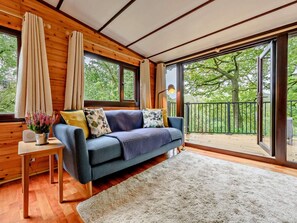 A cozy room with a blue sofa, a white rug, and a wooden floor.
