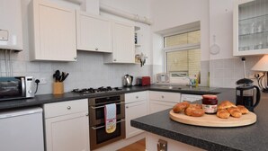 A modern kitchen with white cabinets, a gas stove, a microwave, and a coffee maker. - 2 Bed in Ventnor (oc-75730) (Ventnor)