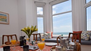 A breakfast setup with croissants, orange juice, and a vase of flowers on a table with a patterned tablecloth. - 2 Bed in Ventnor (oc-75730) (Ventnor)