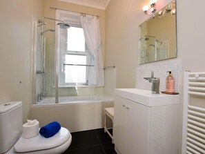 Une salle de bain équipée d’une douche, de toilettes, d’un lavabo et d’un miroir.