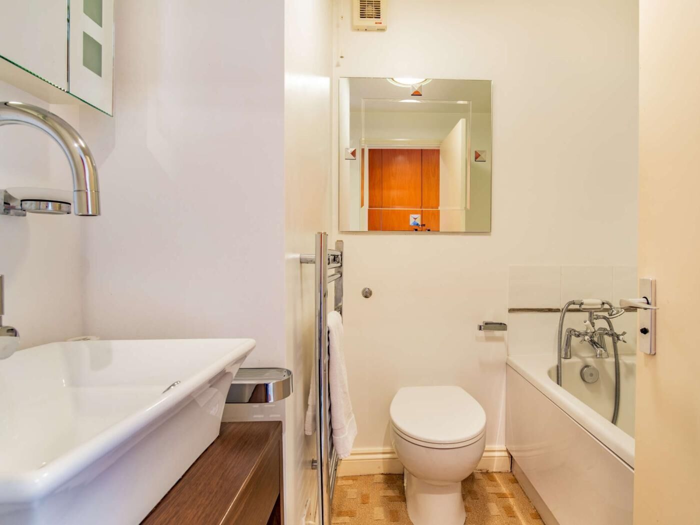 Une salle de bain avec un lavabo, des toilettes et une baignoire, le tout de couleur blanche.