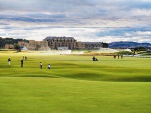 Ein Golfplatz mit einem großen Gebäude im Hintergrund.
