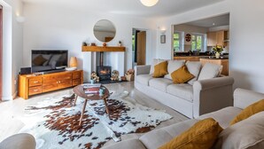 Ein modernes Wohnzimmer mit Kamin, einer Couch, einem Couchtisch und einem Fernseher.